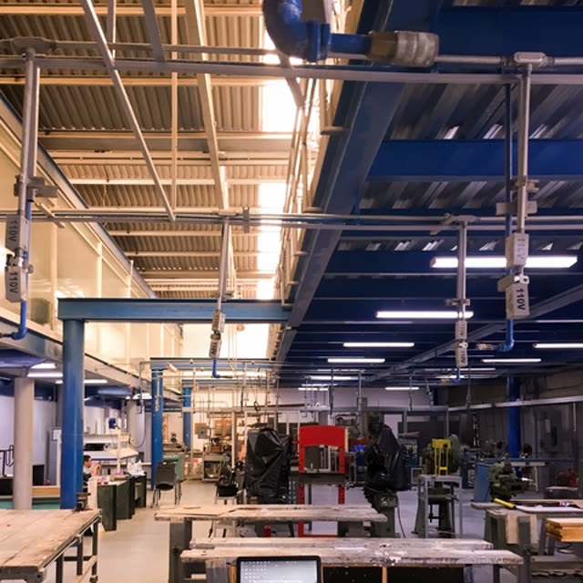 A workshop floor with overhead pipework and machinery