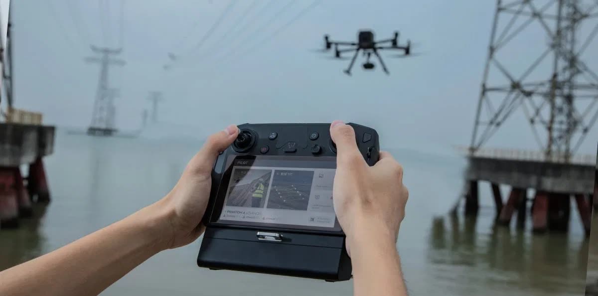 Hands operating a drone controller, the aircraft in flight above