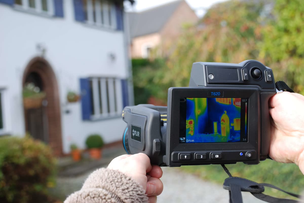 A handheld thermal imaging camera showing a color heat map